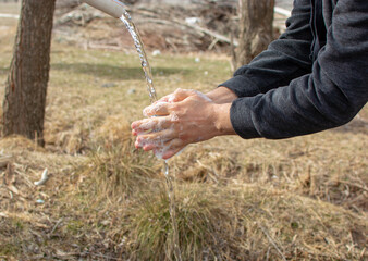 a man washing his hands in the field. We should wash our hands frequently with soap against viruses.