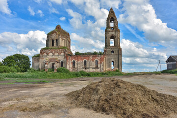 Fototapeta na wymiar ruined church with a bell tower overgrown with grass against a cloudy sky, side view