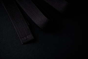 Black karate (judo) belt on dark background. Close up. Copy space. 