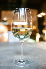 Glass of white wine in restaurant setting.