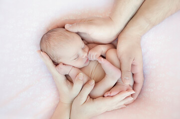 Newborn baby sleeps on blanket. Time to sleep for infant. Parents hands protect baby. Holding a...