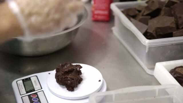Weighing cookie dough on a scale and packaging the chocolate sweets for sale - isolated