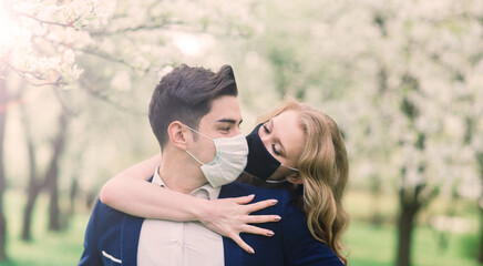 Young loving couple walking in medical masks in the park during quarantine on their wedding day.