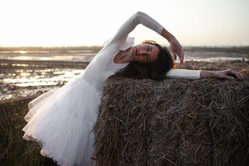 Girl dressed in tulle in a warm sunset on a straw background