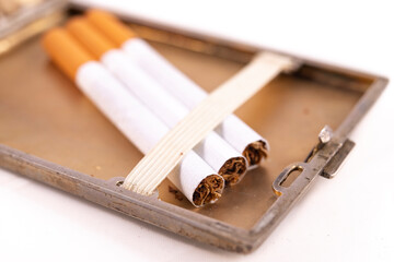 Cigarettes in a metal cigarette case. Stimulants for adults dangerous to health.