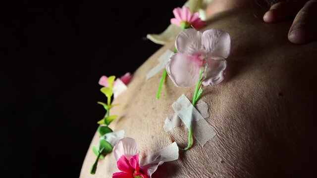 Old grandmother with flowers. Flowers on the old back of the grandmother. The concept of forgiving offenses. Treat mental wounds. Backstab. Talk behind your back.To hope for the best. Spiritual beauty