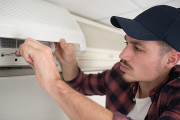 male technician cleaning air conditioner indoors
