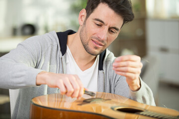 man repairs guitar cords