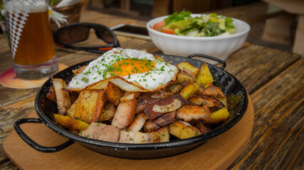 dish served with baked egg, potatoes and meat served typically in an austrian moutain hut.