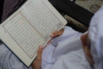 Naklejka premium Klaten, Indonesia, March 12, 2021. A Muslim woman is reading the holy Koran 