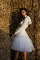 Girl dressed in tulle in a warm sunset on a straw background