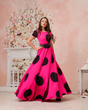 Young beautiful female fashion model wearing vivid pink full length polka dot dress