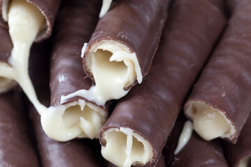 milk filling flows out of waffle tubes in chocolate