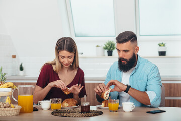 Obraz na płótnie Canvas Couple having croissants for breakfast at home