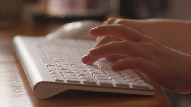 Child fingers typing on the white computer keyboard