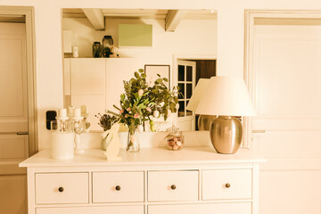 Green branches decorated with eggs. Easter decoration in the house. Spring mood. Table decorations for Easter. Sideboard with a lamp and hanging Easter eggs.