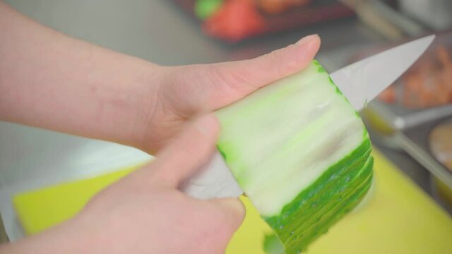 Cuts a cucumber into thin strips