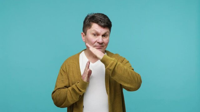 I need more time! Tired dissatisfied mature dark haired man in white t-shirt and cardigan showing time out gesture with hands, need break. Indoor studio shot isolated on blue background