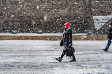 People walk on stret under snowfall