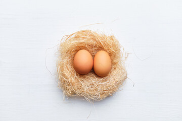 Two eggs in a nest of dried grass and branches on a wooden table. Happy easter concept.