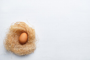 Egg in a nest made of dried grass and twigs on a wooden table. Happy easter concept. Copy space.