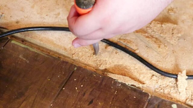 using a chisel and hammer to pry out old nails from subflooring