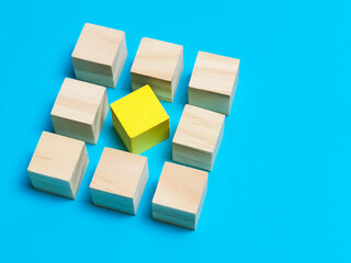 Diversity, individuality or difference concept. Selective focus wooden cubes with yellow color at the center isolated on blue background.