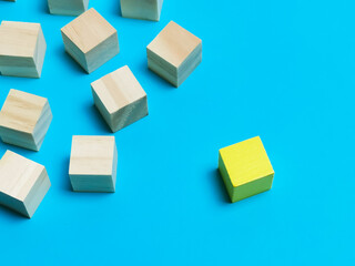 Dissenting opinion, stand out and different concepts. Selective focus wooden cubes with one yellow color isolated on blue background.