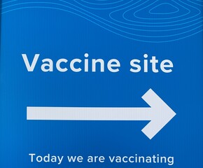Covid-19 vaccine sign, direction to the vaccinating place. Blue background with white text sign.
