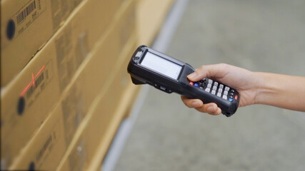 Close up hand scanning products with barcode scanner in warehouse.
