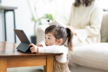 タブレットPCを見る日本人の女の子と読書をする母親