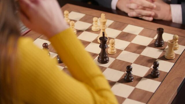 Female chess player moving her king on a chessboard and stop the counter. Close-up shot