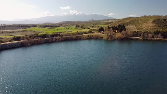 Drone aerial view in Spain above the blue lake flying back close to  Moncayo snow mountain landscape