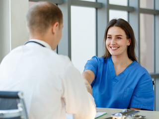 Woman Caucasian patient smile look comfortable and handshaking with a doctor. Focus to woman patient in an examination room at the hospital on morning day with light