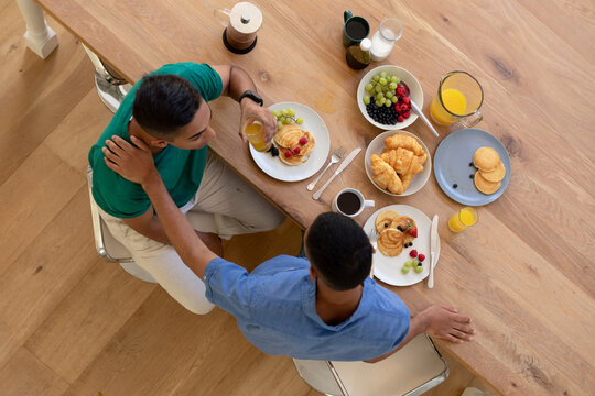 Diverse Gay Male Couple Eating Breakfast Together And Talking