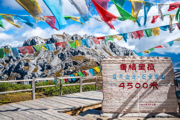 Sign and view of the 4500m high Shika snow mountain summit with prayer flags in Shangri-La Yunnan China
