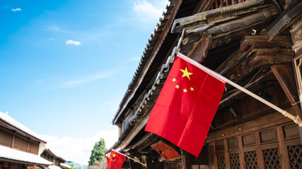 Chinese flag hanging on an ancient wooden house and blue sky with copy space Dali old town Yunnan...
