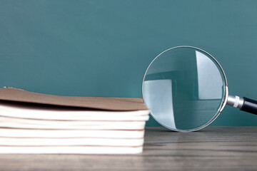 A stack of notebooks and a magnifying glas