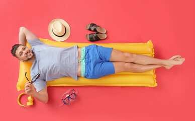 Handsome man lying on inflatable mattress against color background - Powered by Adobe