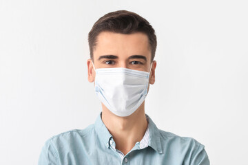 Young man wearing medical mask on white background