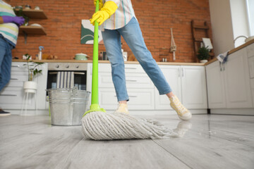 Young woman mopping floor in kitchen