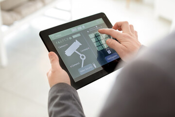 Man with tablet computer using smart home security system application