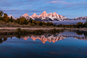 Fototapeta premium dramatic wintry autumn sunrise of the Grand Tetons mountain range and its reflection.