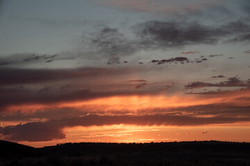 A stunning orange winter sunset for cloud replacement with pastel coloring and cloudy covered sky with blue poking through.