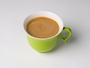 Coffee in a green cup on a white background. Beautiful creamy foam. Studio photography
