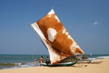 In Negombo, Sri Lanka, an outrigger fishing boat (oru) with a colorful sail rests on the beach, awaiting its next trip out onto the Indian Ocean.