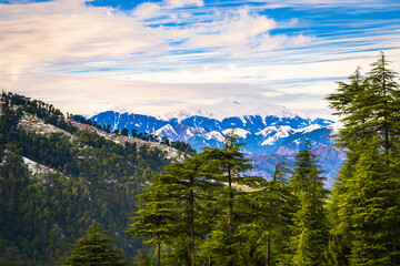 Landscape with snow and mountains. Sunset view of a scenic village during winter in the backdrop of the Himalayan mountains. Himachal Pradesh, India.	
