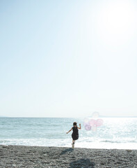 風船をもって海に向かって走る女の子