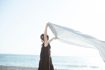 海で布を風に靡かせて遊ぶ女の子