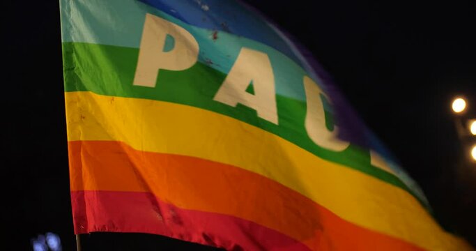 Waving rainbow pace flag at night, closeup view. Peace and human rights concept